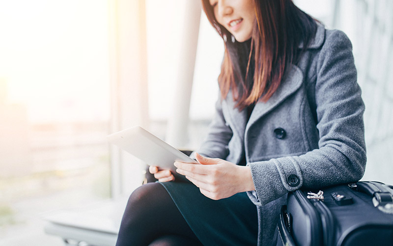 Woman sitting in the airport looking at her tablet